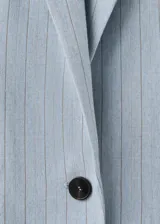 Blazer de corte sastre en color celeste con estampado de raya diplomática, cuello de solapa con muesca, cierre frontal de un botón, bolsillos con solapa en los laterales y bolsillo de ribete en el pecho.
