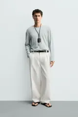 Pantalón barrel fit de hombre, confeccionado en denim de algodón color crudo. Presenta cintura con pliegues frontales, bolsillos laterales y cierre con cremallera y botón.