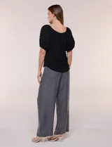 Blusa blanca de tela texturada y silueta fluida, con escote en U y frunces. Cuenta con mangas cortas abullonadas con elástico en los puños y ruedo redondeado.