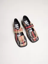 Zapatos tipo guillermina con punta cuadrada, confeccionados en lona resistente con estampado de cuadros escoceses en tonos beige, rojo y negro. Presentan una correa ajustable con hebilla metálica color bronce y una suela con taco de 4 cm.