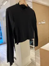 Remera de morley color mostaza, de manga larga, con cuello alto fruncido y terminaciones fruncidas en las mangas.