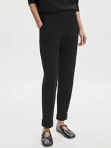 Pantalón negro de tejido DoubleSoft, corte ajustado con puños enrollados, pinzas delanteras y traseras, y bolsillos con forma.