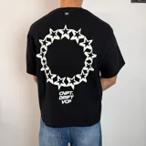 Remera negra de corte boxy con estampa en la espalda que presenta un círculo formado por estrellas blancas y el texto CNPT. DRIFT VCP en la parte inferior.