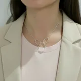 Gargantilla de plata 925 con cadena fina y dije compuesto por tres aros entrelazados. Dos aros laterales pequeños y un aro central más grande.