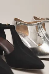 Sandalia de cuero color bordó, con acabado charolado, punta fina y tacón cuadrado de 5 cm. Presenta una tira en forma de T sobre el empeine y una correa con hebilla alrededor del tobillo.