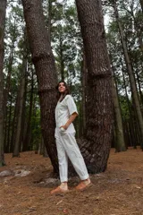 Mono blanco de gabardina de algodón, corte clásico con cierre frontal, pantalón largo con bolsillos, manga corta y cintura fruncida en la espalda.