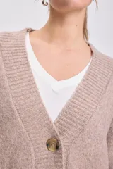 Cardigan de punto en color beige, con escote en V, cierre frontal de botones y mangas largas con puños acanalados.