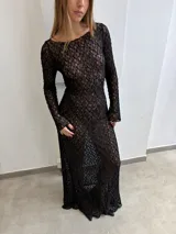 Vestido largo de encaje negro con diseño de manga larga y corte ajustado, confeccionado en tejido transparente con patrón calado.