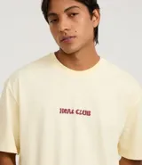 Remera de algodón color amarillo pálido, corte relajado y cuello redondo, con un pequeño estampado en el pecho con el texto "Heat Club" en tipografía estilizada color bordó.