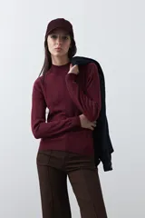 Polera de tejido de punto en color bordó, con cuello alto y diseño tramado vertical. Presenta un corte ajustado al cuerpo con puños y ruedo acanalados.