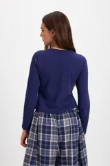 Blusa de algodón con cuello redondo, manga larga y cierre frontal con botones a tono. Presenta un diseño ajustado al cuerpo.