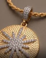 Collar de la línea Imperial, compuesto por una cadena de eslabones tipo cuerda en color dorado y un gran dije redondo con textura punteada y un diseño central de estrella incrustado de piedras brillantes.
