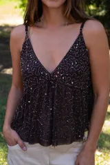 Blusa de tirantes finos con escote en V, confeccionada en gasa fluida color marrón. Presenta un diseño con bordado de lentejuelas y canutillos en el busto y líneas verticales de pedrería a lo largo del cuerpo.