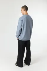 Buzo de cuello redondo en color crema, confeccionado en algodón, con detalle de logo en forma de cruz bordado en el pecho.