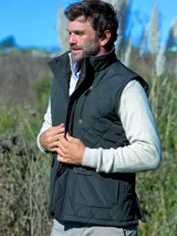 Chaleco acolchado de color azul oscuro con diseño de rombos, cuello alto, cierre frontal con botones a presión y bolsillos delanteros con solapa y detalles en contraste.