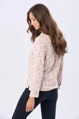 Camisa de jersey de algodón color beige con estampado floral en tonos rosados y marrones, cuello camisero, manga larga con puños abotonados y cierre frontal con botones.