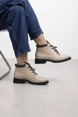Borcego de cuero vacuno color marrón caramelo con acabado mate, estilo combate y caña baja. Cuenta con cordones marrones, panel de gamuza oscura en el cuello y suela de caucho negra tipo tractor con costura blanca visible.