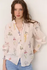 Camisa de manga larga color arena con delicado estampado floreado, cuello mao con volados, escote en V con botones frontales y puños fruncidos elastizados.
