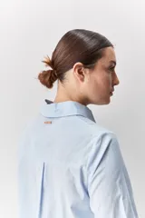 Camisa de algodón blanca, de calce relajado, con cuello clásico, mangas largas y cierre frontal con botones.