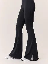 Calza acampanada de tiro alto en color negro, confeccionada con tejido de alta compresión y diseño ajustado que se ensancha en la parte inferior con pequeños tajos laterales en los tobillos.