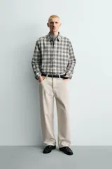 Camisa de corte boxy fit confeccionada en tejido de algodón con elasticidad. Presenta un diseño a cuadros, cuello solapa, manga larga con puños abotonados, bolsillo de vivo en el pecho y cierre frontal con botones.