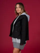 Chaqueta corta negra de paño con doble botonadura y solapas amplias.
