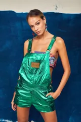 Enterito corto verde metalizado con tirantes regulables y etiqueta de cuero con el logo de la marca en el bolsillo del pecho.