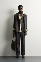 Blazer cruzado de corte relaxed fit, confeccionado en mezcla de lana de color marrón oscuro jaspeado. Presenta solapas de muesca, doble botonadura frontal multiposición y bolsillos con solapa en la cadera.