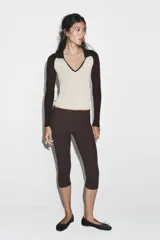 Camiseta de manga larga, corte slim fit, con cuerpo color beige claro y mangas y cuello polo en color marrón oscuro. Presenta un escote en pico bajo el cuello polo.