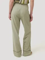 Pantalon de lino organico color verde militar, de corte recto y tiro alto, con detalles de calado negro en la cintura y en los dobladillos.