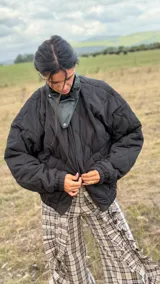 Campera puffer negra con diseño matelaseado en rombos, cuello alto con detalle de solapa en cuero sintético, mangas largas con puños elásticos y ruedo ajustado tipo bomber.
