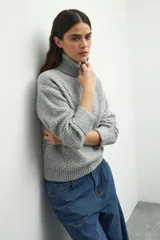 Polera de cuello alto con textura tramada, manga larga con puños acanalados y diseño holgado.