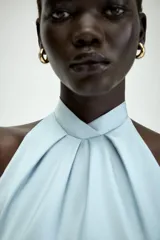 Vestido midi de satén color celeste, con cuello halter y detalle de lazada en la espalda descubierta.
