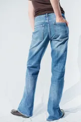 Jeans de denim de algodón con leve stretch, tiro alto, corte ajustado hasta la rodilla y acampanado desde la rodilla al bajo. Presenta cierre y botones frontales, y solapas de bolsillo decorativas con botón en la parte delantera.