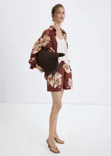 Camisa de manga larga color marrón con estampado floral grande en tonos beige y blanco, cuello camisero y cierre frontal con botones.