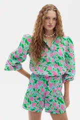 Camisa celeste con estampado floral en tonos rosados y verdes, de lino, con cuello camisero, mangas largas abullonadas y cierre frontal con botones.