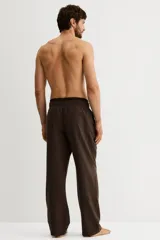 Pantalón de franela de algodón suave, color marrón con patrón de cuadros pequeños. Cuenta con cintura elástica con cordón ajustable y bolsillos al bies. El corte es relajado, pero no oversized.
