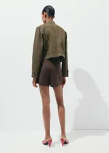 Minifalda marrón estilo pareo de corte evasé, confeccionada en mezcla de algodón y lino, con cierre lateral.