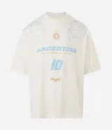 Remera de corte oversized color blanco, con cuello redondo y manga corta. Presenta una estampa frontal temática de Argentina en tonos celestes y dorados, que incluye el número 10, un sol y detalles gráficos tribales.