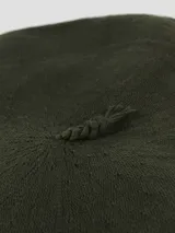 Boina de hilo tejida en color beige, con forro interior oscuro y etiqueta de la marca Tolosa.