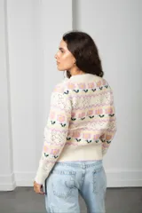 Cárdigan tejido de punto en color beige con diseño de flores y guardas caladas. Presenta escote en V, cierre frontal con botones y terminaciones acanaladas en puños y ruedo.
