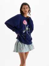 Buzo azul marino de corte oversize y cuello redondo, con diseño gráfico estampado de una flor y una abeja en el frente.