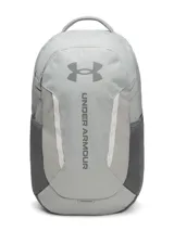 Mochila Under Armour modelo Hustle 6.0, color gris, con tecnología UA Storm resistente al agua. Cuenta con compartimento acolchado para portátil, bolsillo para calzado o ropa sucia, bolsillos laterales de malla y sistema Molle para sujeción.