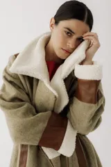 Gamulán de paño en color beige jaspeado con detalles en cuero sintético marrón y forro de corderito sintético blanco. Presenta cierre frontal cruzado, cuello solapa, bolsillos laterales y puños con vuelta.