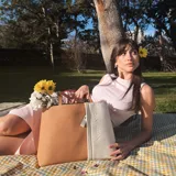 Cartera tipo tote de cuero sintético con diseño combinado en tono gris y blanco, textura granulada, asas largas para el hombro y cierre superior.