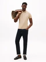 Chomba de mangas cortas color beige, corte slim, con cuello polo y cartera de dos botones. Logo de Tommy Hilfiger bordado en el pecho.