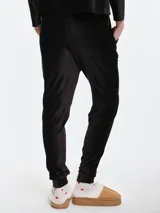 Pantalón de dormir tipo jogging confeccionado en plush acanalado de tacto suave. Presenta cintura elastizada con cordón ajustable, bolsillos laterales y puños elastizados en los tobillos.