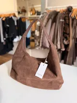 Cartera tipo hobo de diseño relajado, confeccionada en material con textura simil gamuza color chocolate. Presenta una silueta suave, cierre superior y asa corta combinada en simil cuero al tono.
