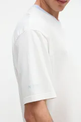 Remera blanca de algodón con textura suave, corte relaxed, manga corta, cuello redondo en contraste de color celeste y un bolsillo aplicado en el pecho.