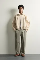 Cazadora cropped fit de algodón color beige, con cuello solapa, manga larga y cierre frontal de cremallera. Cuenta con bolsillos de vivo en la cadera, acabados elásticos y detalle de bordado a tono en el pecho.